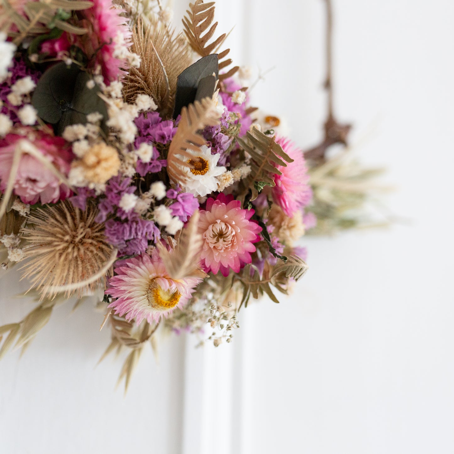 close up of flower arrangement, close up of pink strawflowers and pink statice surrounded my ferns and babys breath