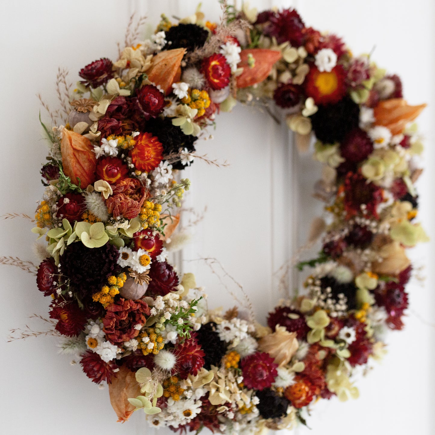 Autumn-themed wreath hung on a white door.