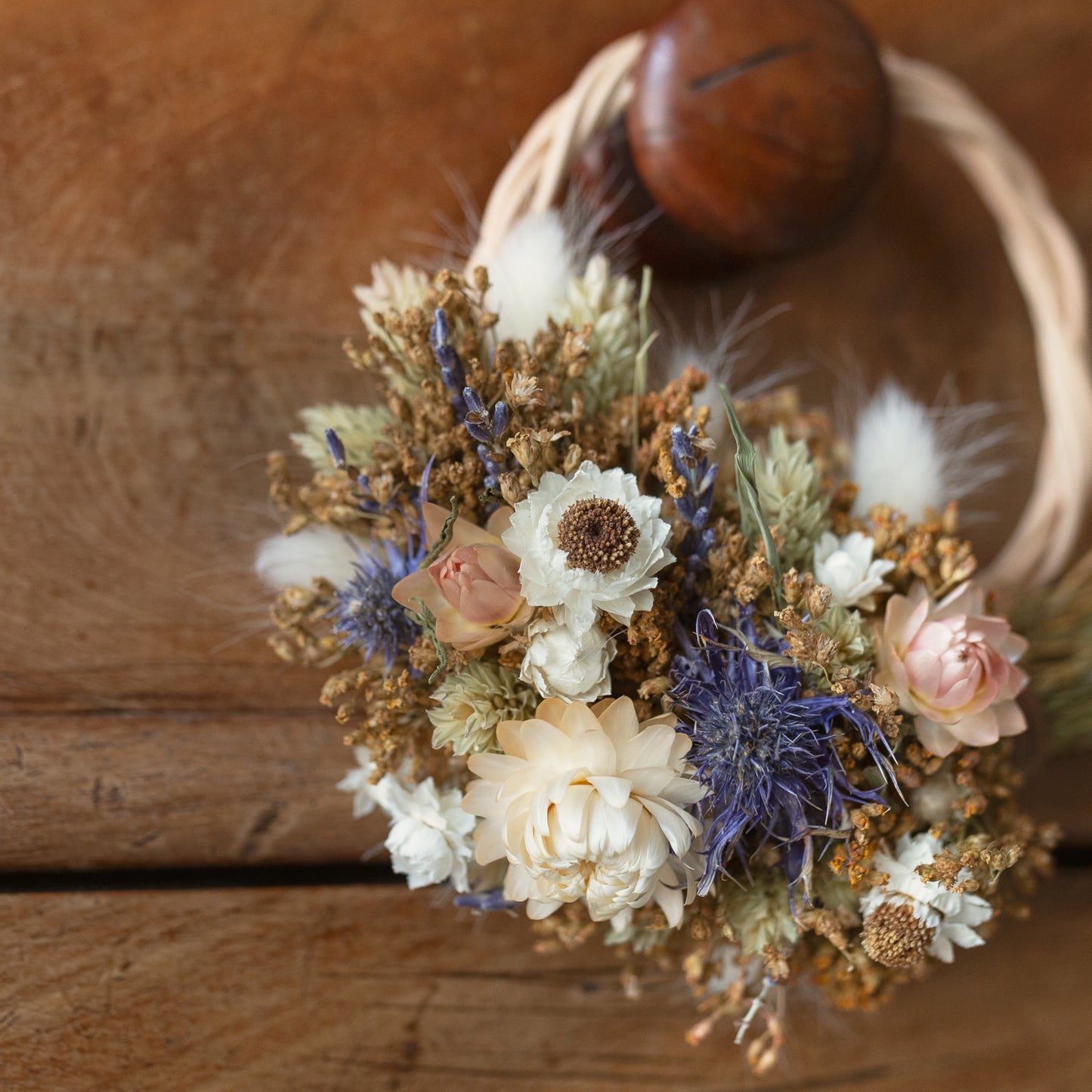 close up of dried flowers on a wicker wreath circle hoop blue thistles and white strawflowers
