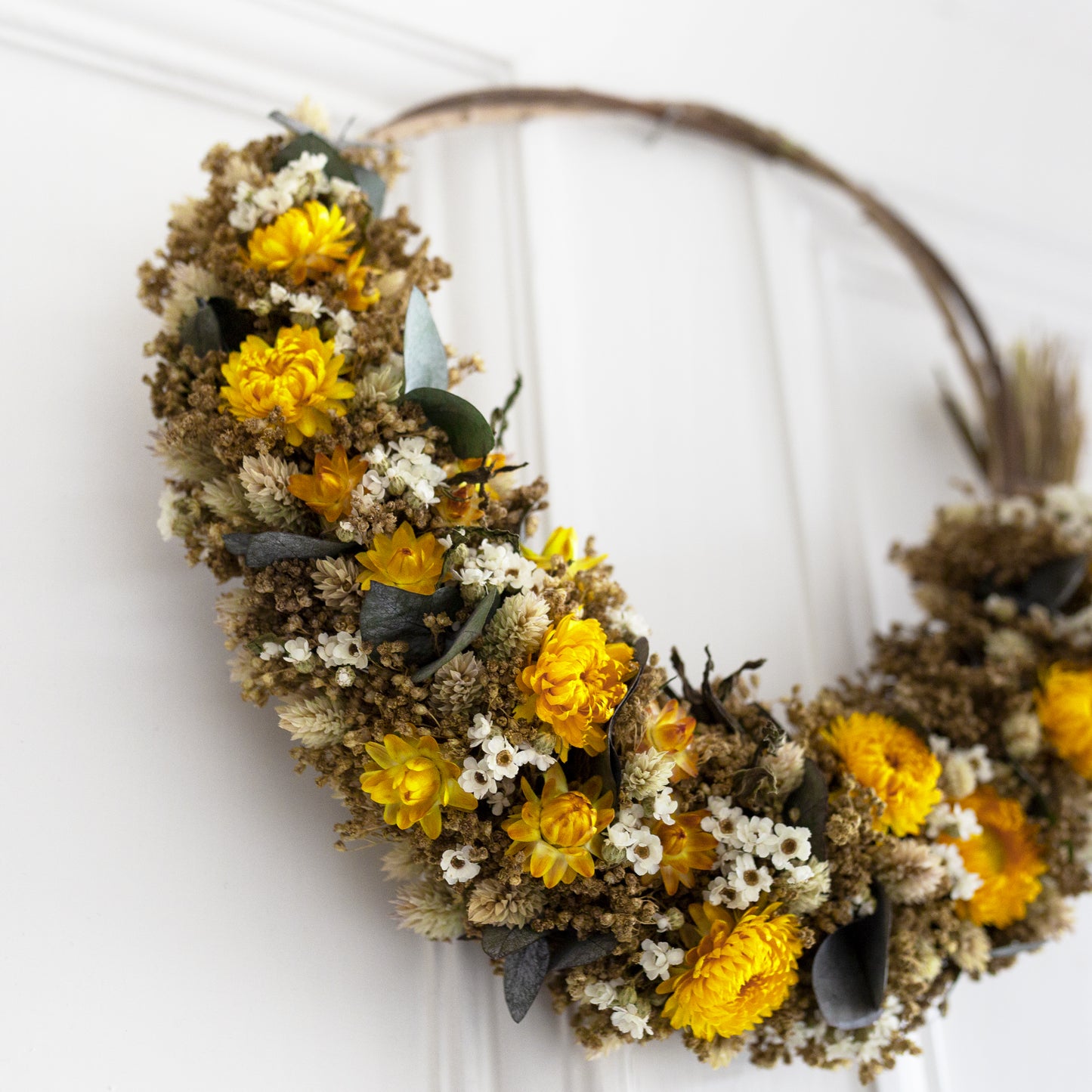 willow wreath close up of yellow strawflower, white daisies and eucalyptus