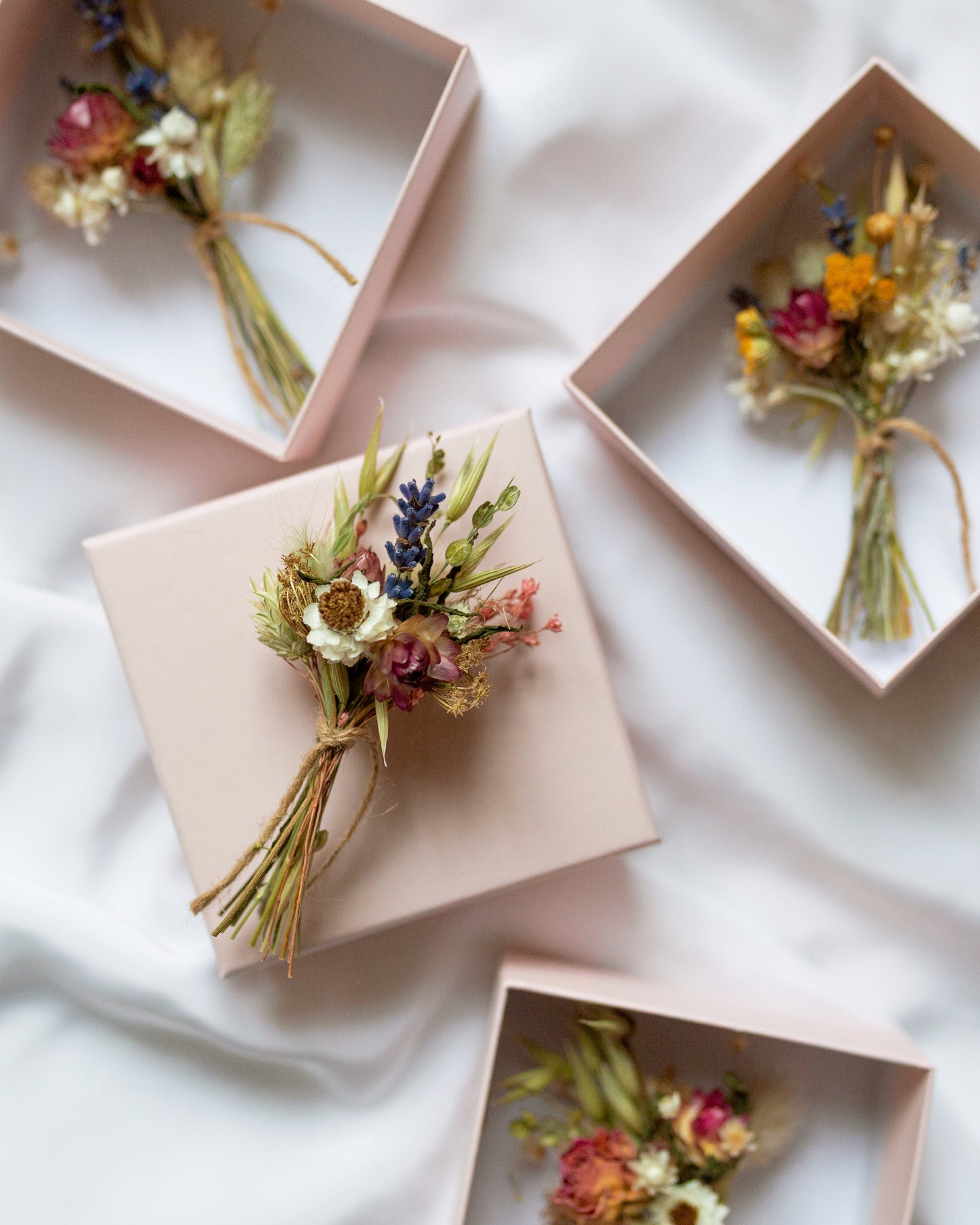 4 mini colourful gift sizes posies. one laid on top of a gift box the other 3 laid inside gift boxes