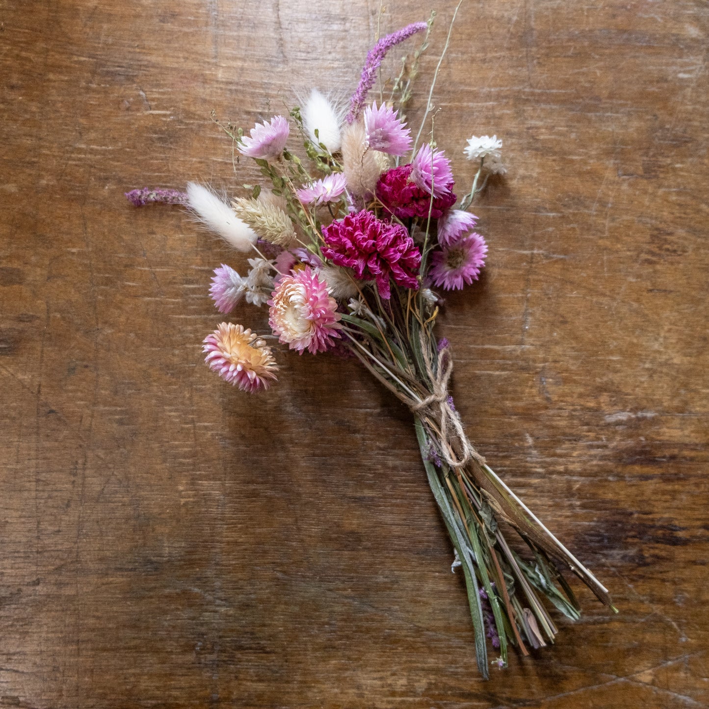 Bouquet posy of pink dried flowers tied with twine on a wooden surface