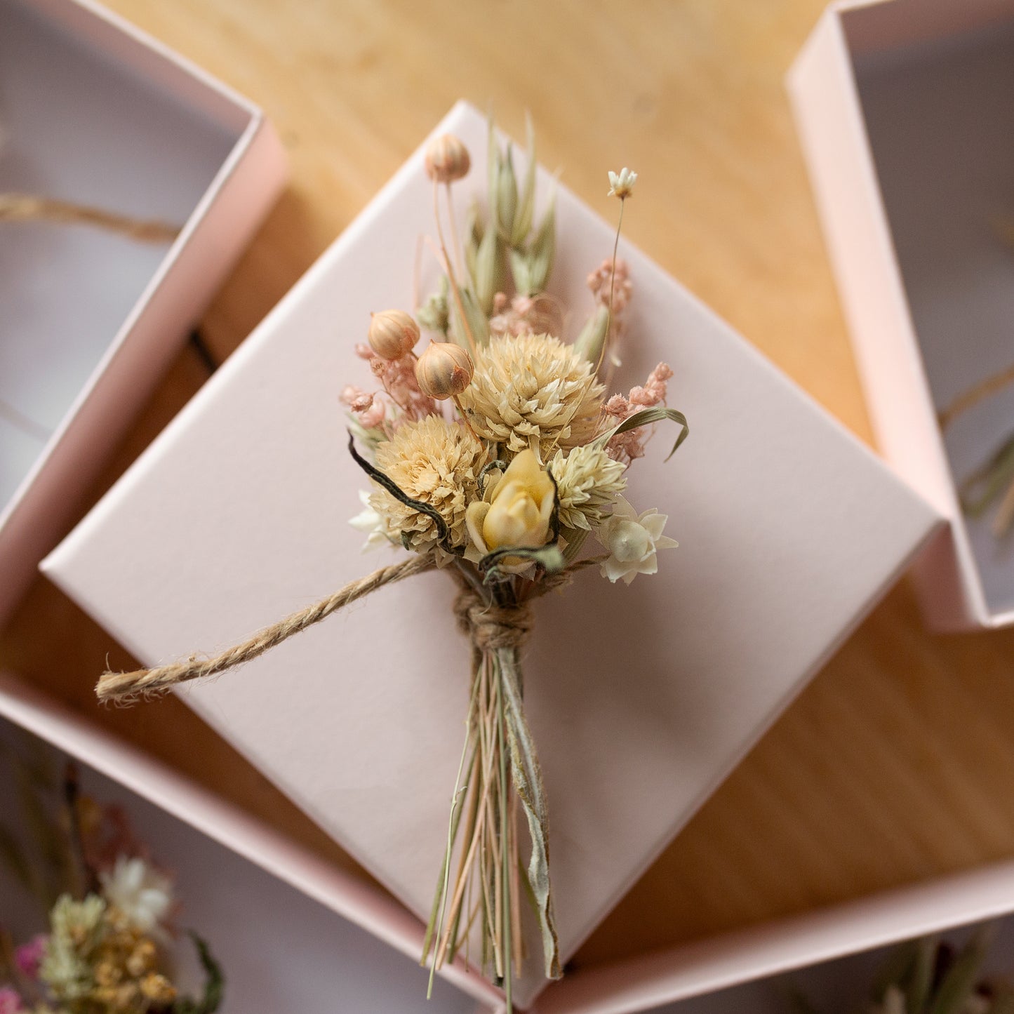 cream and pale pink dried flower mini posy tied with twine on top of a pink gift box