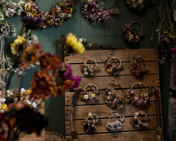 florist studio with wreaths all different sizes hung up on wall and on hangers
