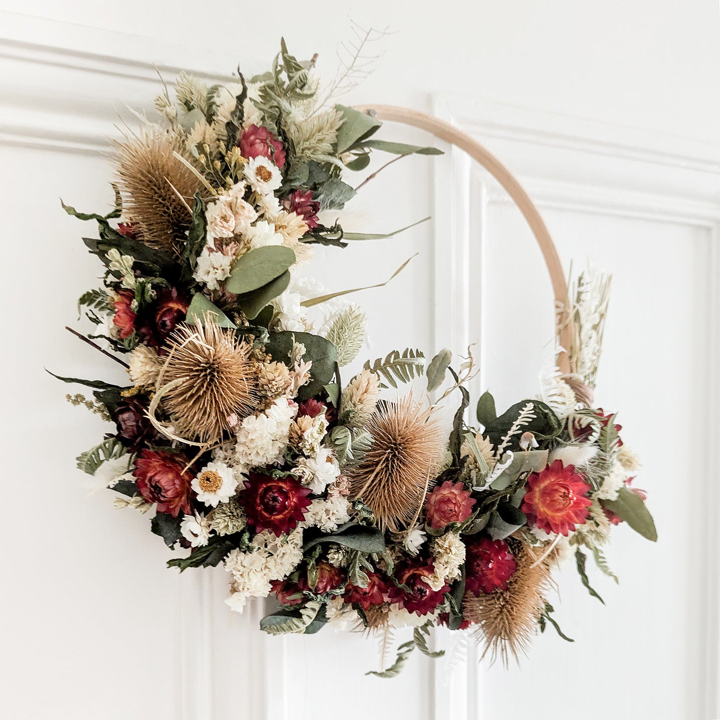 red, green, white and natural coloured dried flower wreath hung on the back  a white door internal door