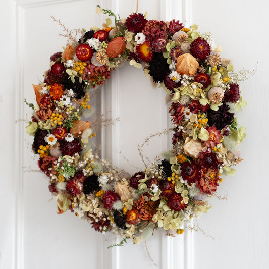 Autumn-themed full circle dried flower wreath on a white door