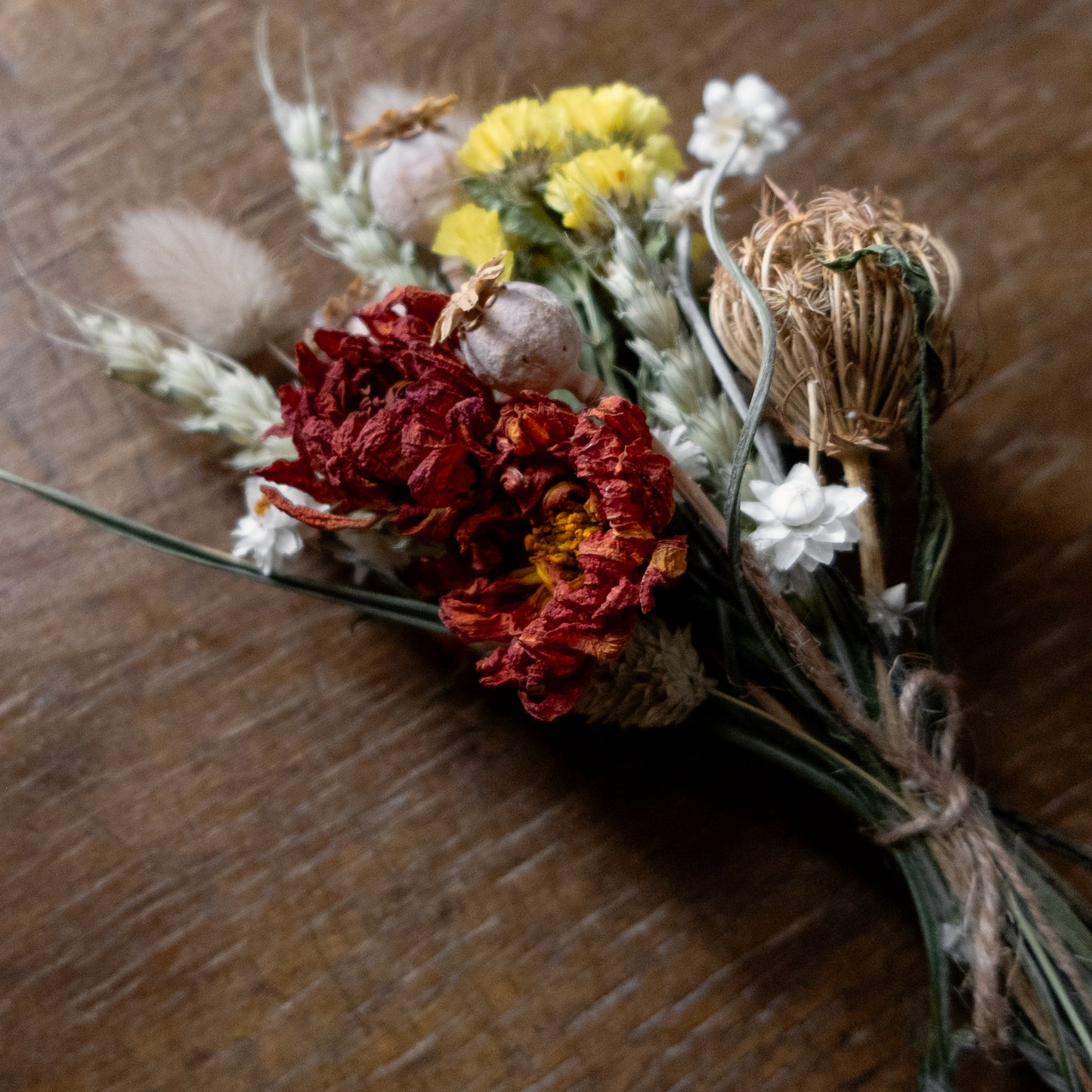 posy bouquet of dried flowers laid on a wooden surface 