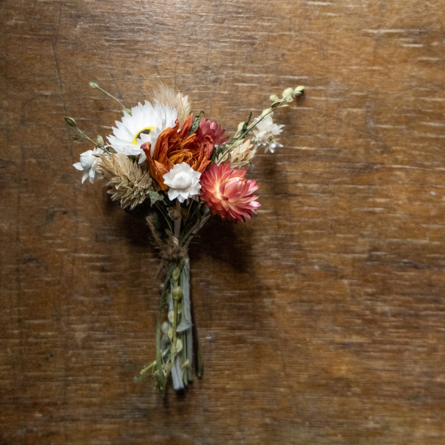 dried flower posy tied together with twine laid on a wood surface