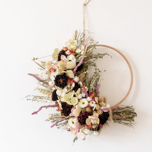 wooden hoop half covered with dried flowers on a white background