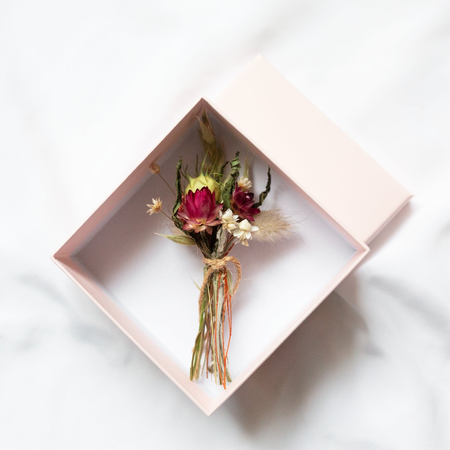 Small bouquet of flowers in a pink  gift box on a white background