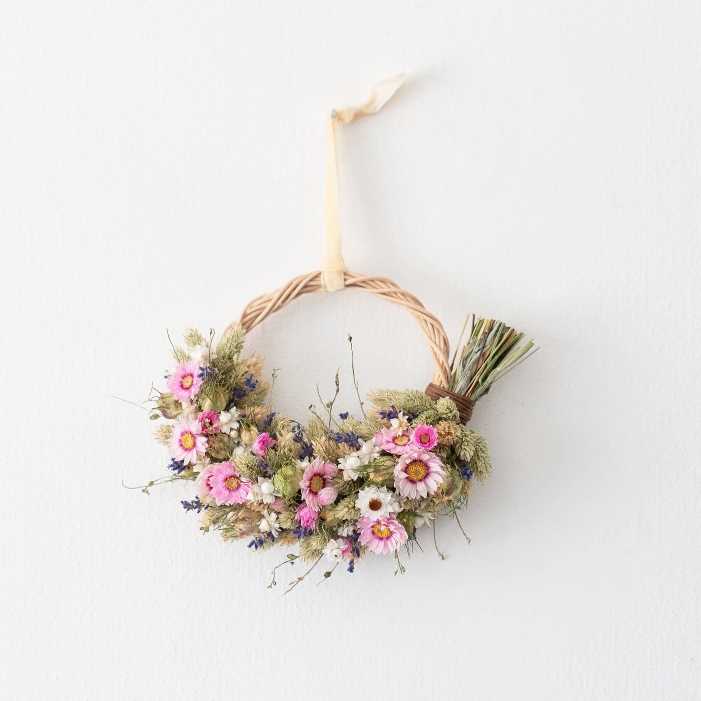 pink and white daisy wreath with lavender. hung on a white door by a cream coloured velvet ribbon