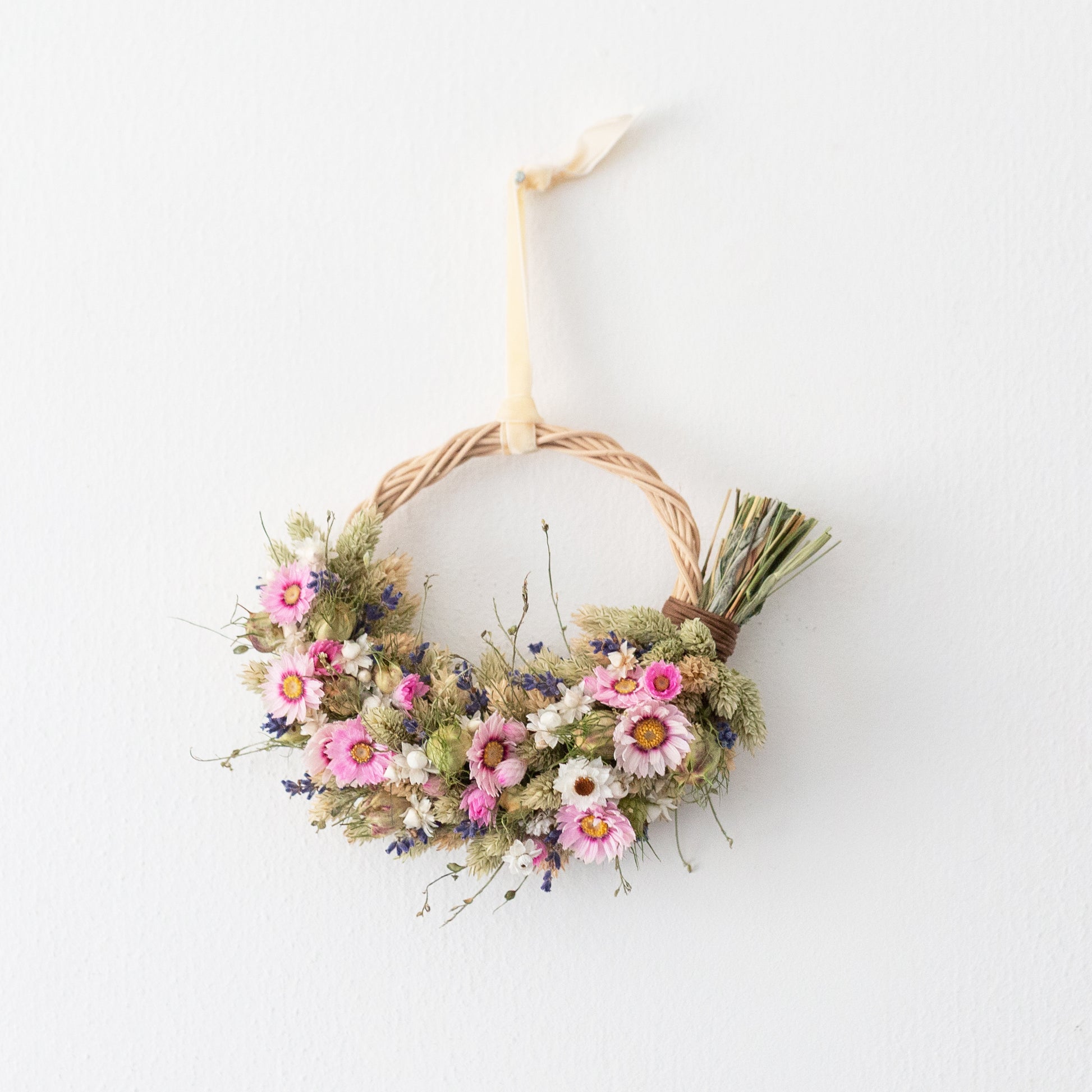 pink and white daisy wreath with lavender. hung on a white door by a cream coloured velvet ribbon