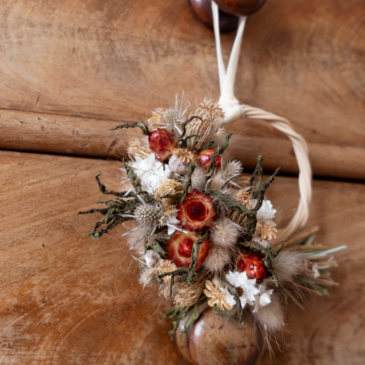 close up of red strawflowers and thistles on a mini flower wreath