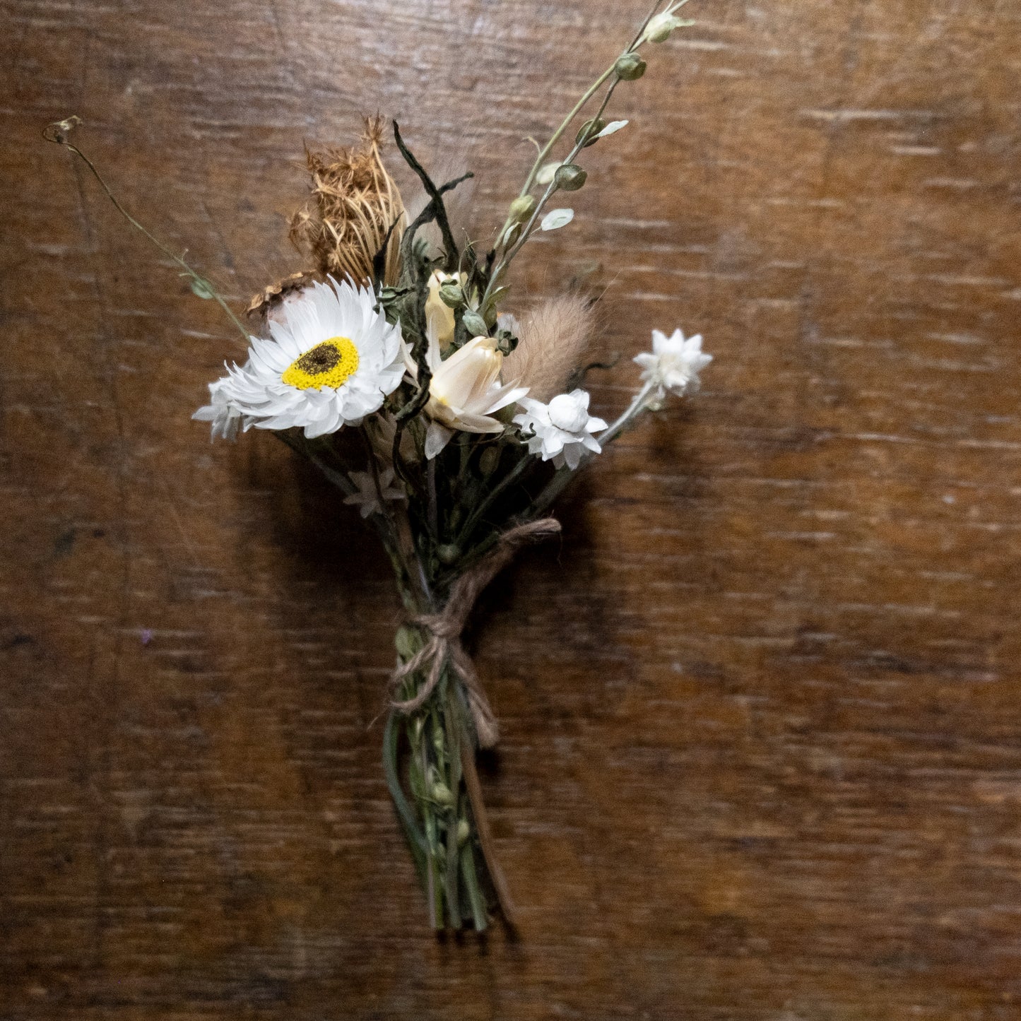 Bouquet posy of dried flowers tied with twine on a wooden surface