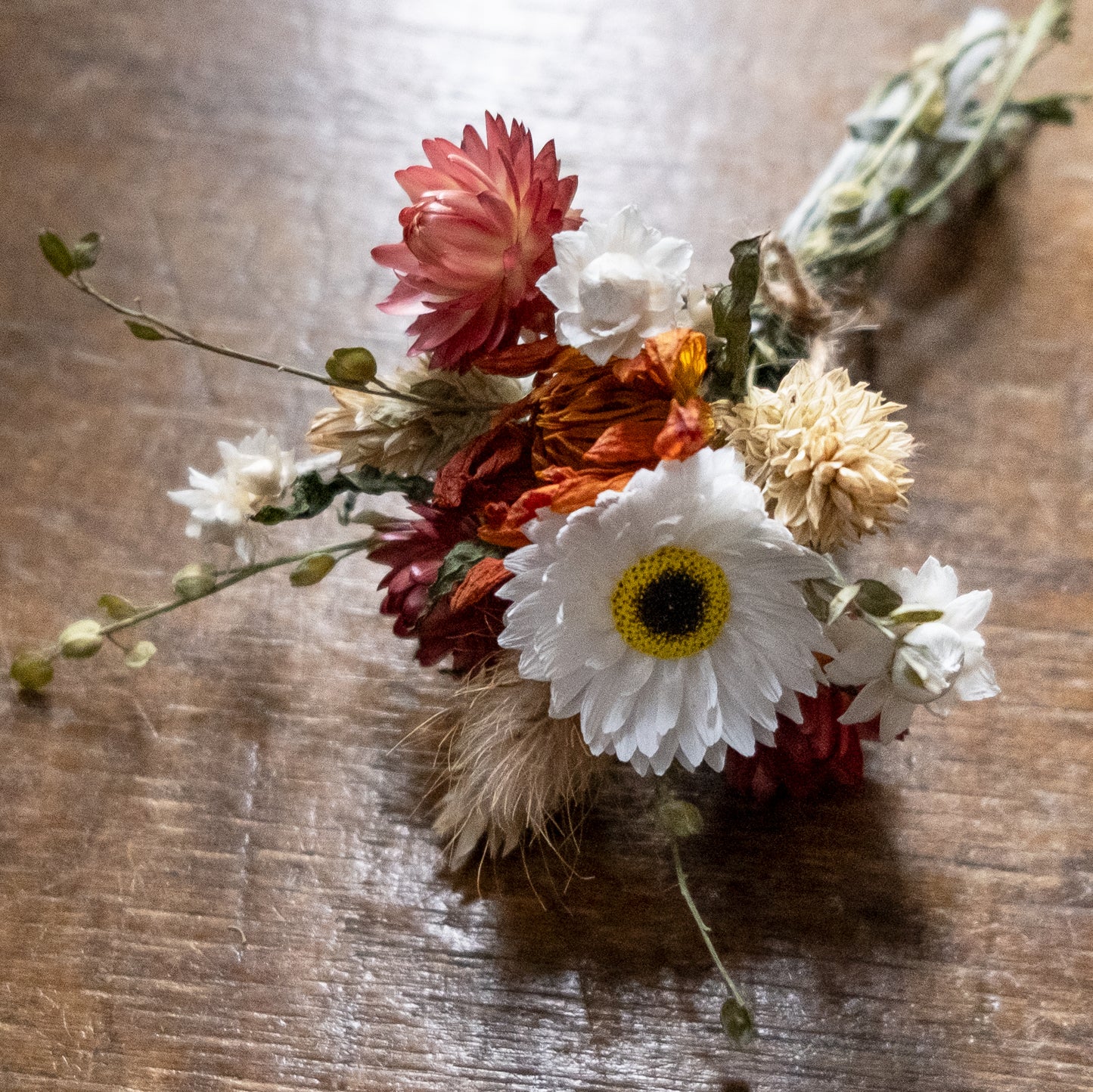 orange dahlia and strawflower posy bouquet of flowers on a wooden surface