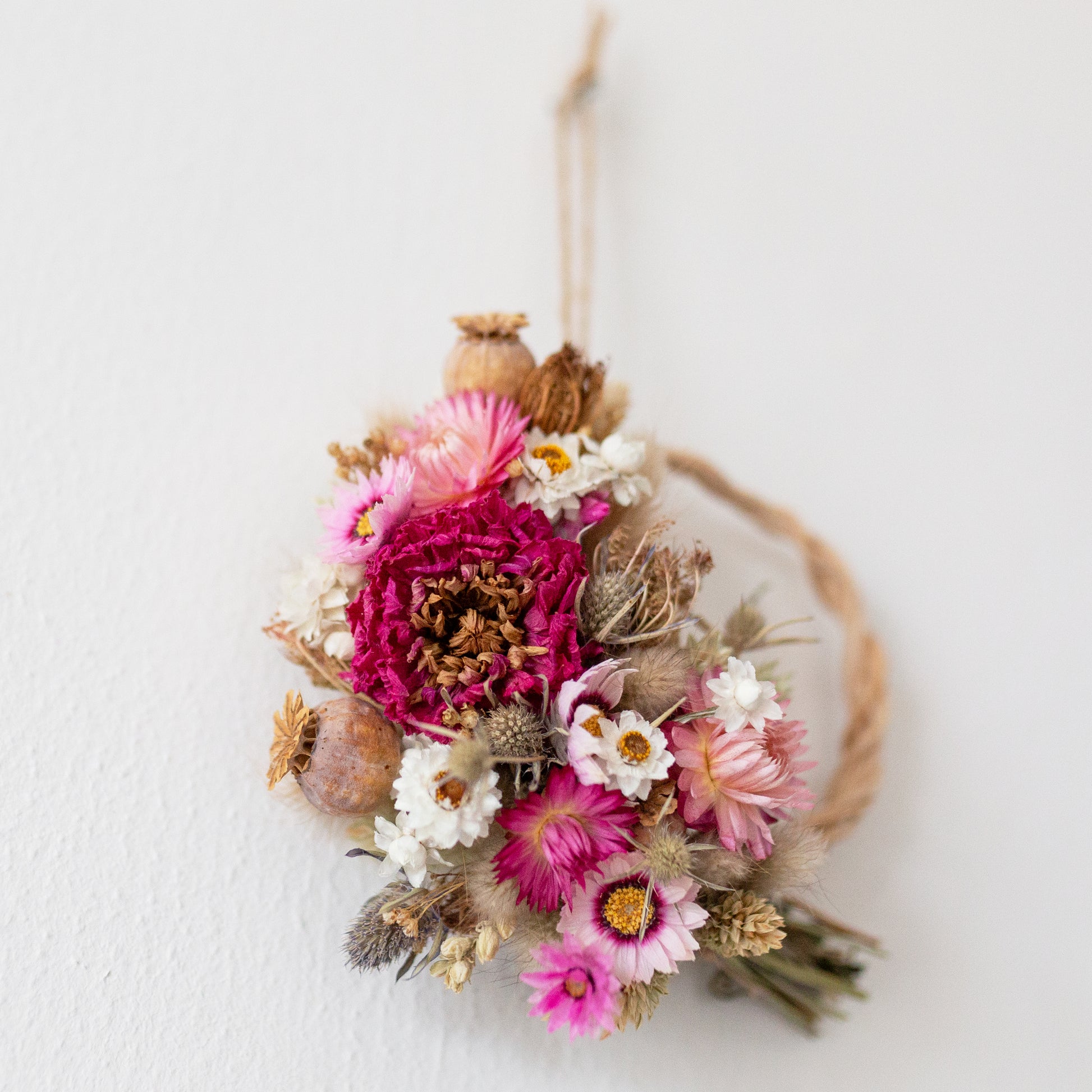 small dried flower half wreath close up of pink strawflowers and pink dahlia