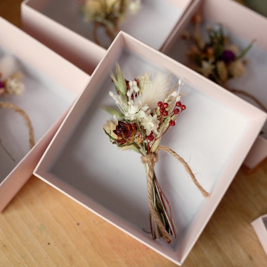 red and white dried flower posy tied together with twine in a pink gift box