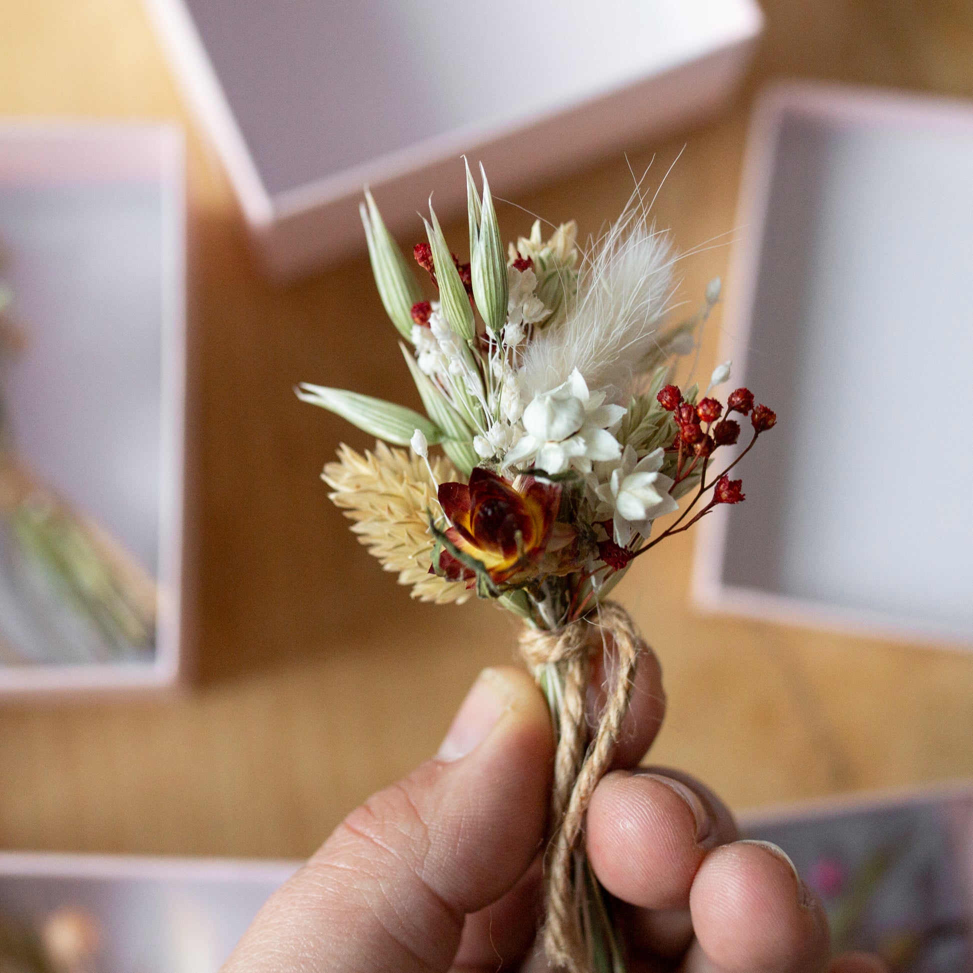 red and white mini dried flower posy held in hand