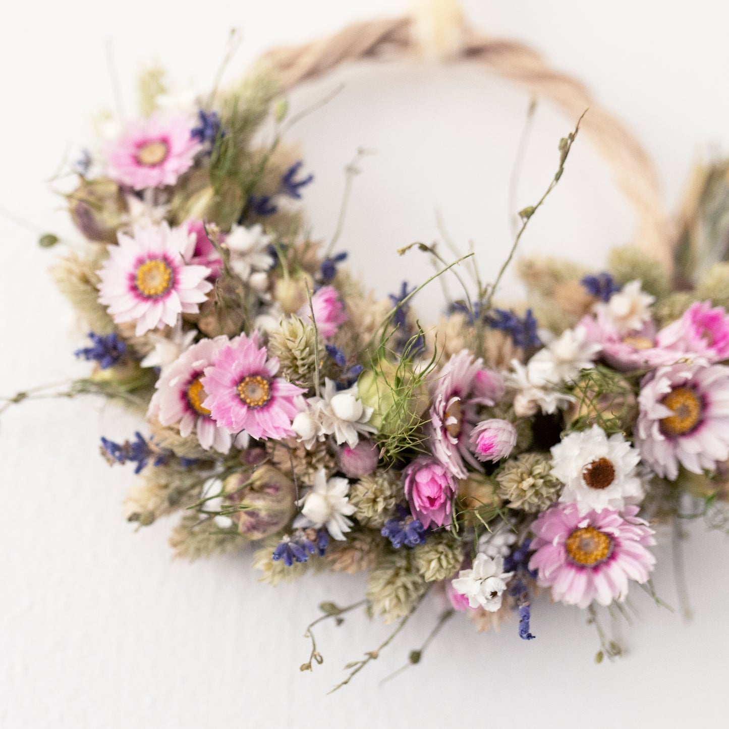 close up of rhodanthe pink daisies and nigella seed heads on a wreath